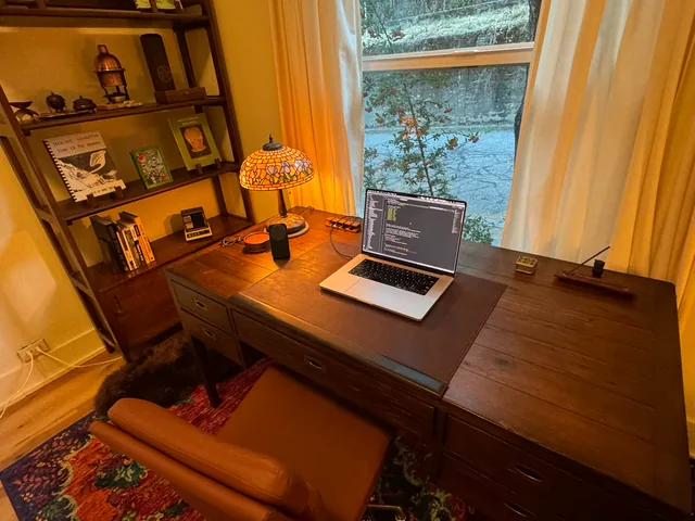 a laptop and glowing stained-glass lamp on the wooden desk where nnyyxx was built