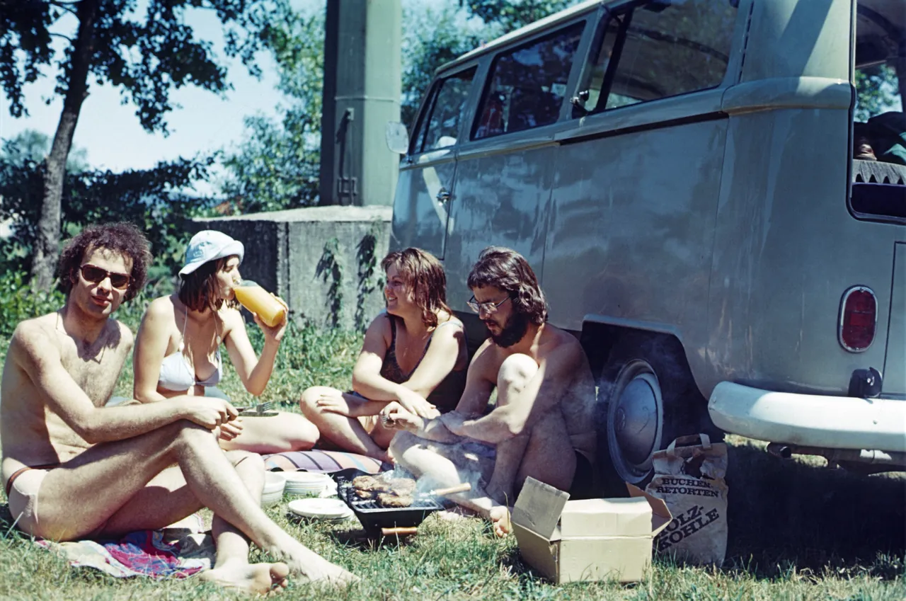 four people sharing a picnic beside a camper van